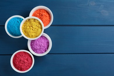 Photo of Colorful powder dyes on blue wooden background, flat lay with space for text. Holi festival