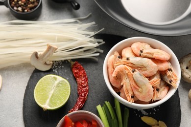 Photo of Different products and black wok on grey table, flat lay