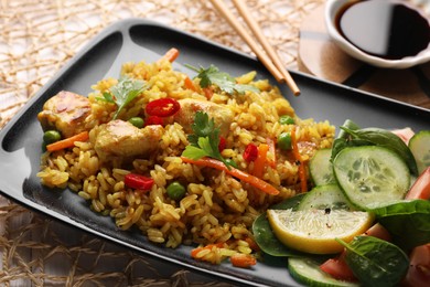 Photo of Tasty rice with meat and vegetables in plate near soy sauce on white table, closeup