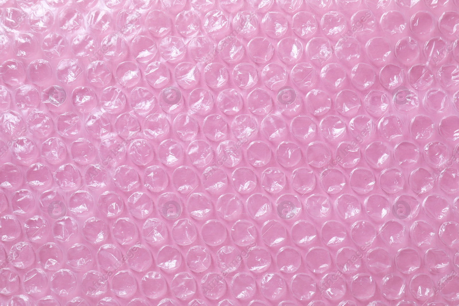 Photo of Transparent bubble wrap on pink background, top view