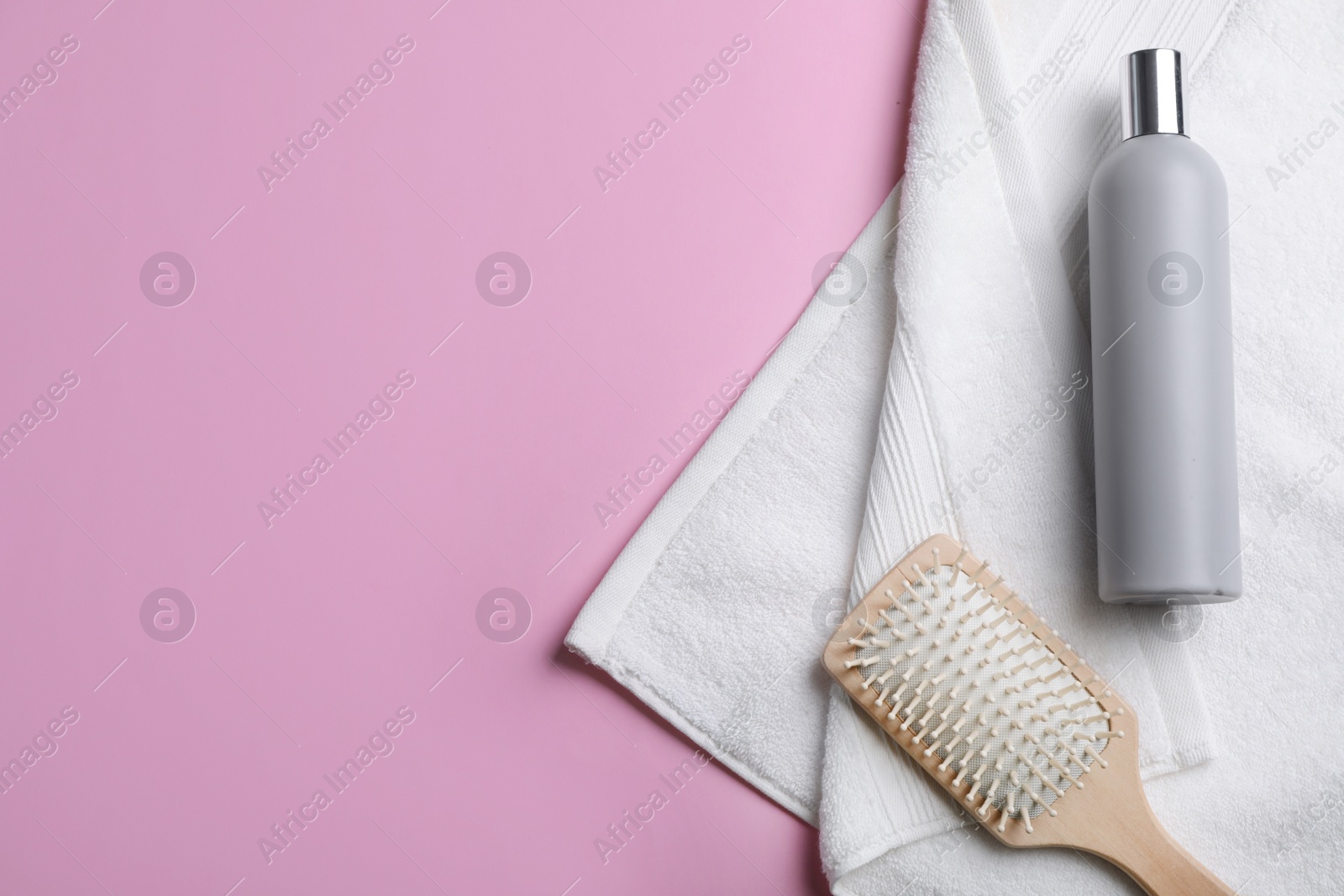 Photo of Bottle of shampoo, towel and brush on color background, top view with space for text