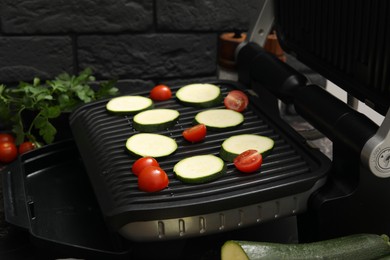 Photo of Electric grill with vegetables on table, closeup