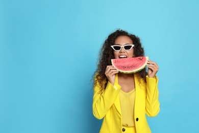Photo of Beautiful young African American woman with watermelon on light blue background. Space for text
