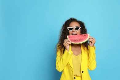 Beautiful young African American woman with watermelon on light blue background. Space for text