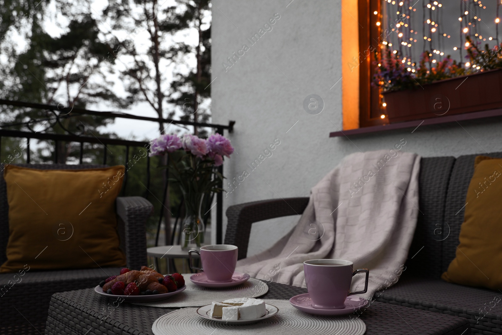 Photo of Rattan table with drink and food on outdoor terrace in evening