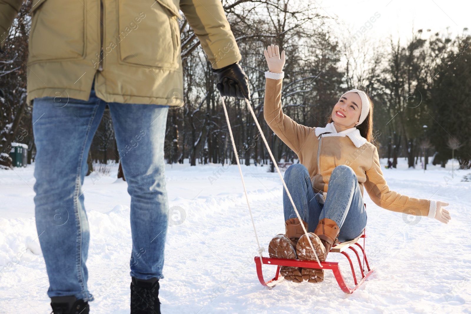 Photo of Man pulling his girlfriend in sleigh outdoors on winter day