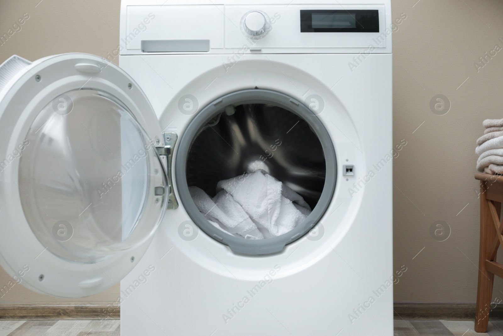 Photo of Washing machine with dirty towel in laundry room