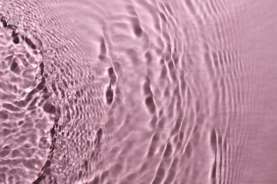 Photo of Rippled surface of clear water on pink background, top view