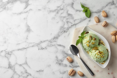 Photo of Delicious pistachio ice cream on marble table, flat lay. Space for text