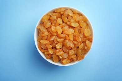 Photo of Bowl with raisins on color background, top view. Dried fruit as healthy snack