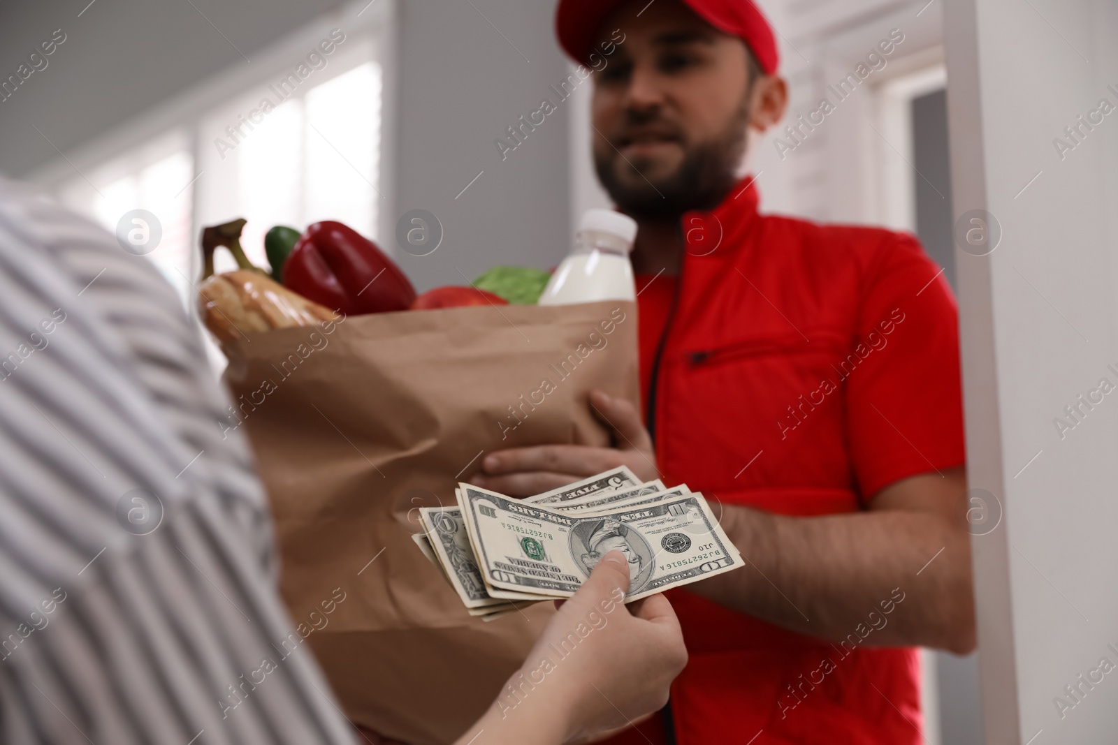 Photo of Young woman giving tips to courier indoors, closeup