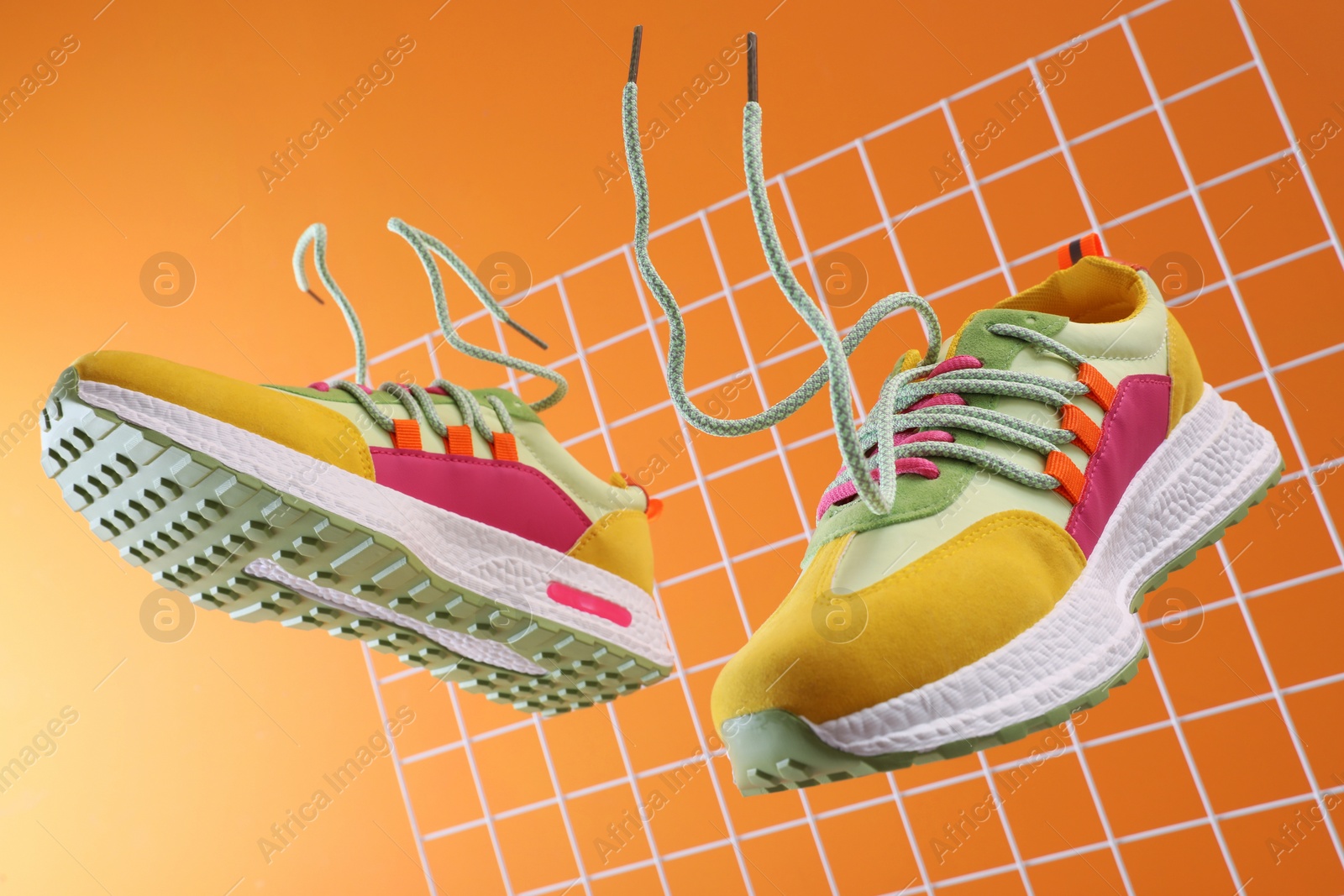 Photo of Stylish presentation of trendy sneakers on orange background