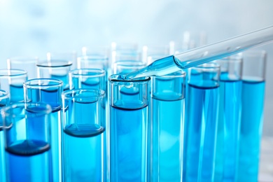 Dropping sample into test tube with blue liquid, closeup