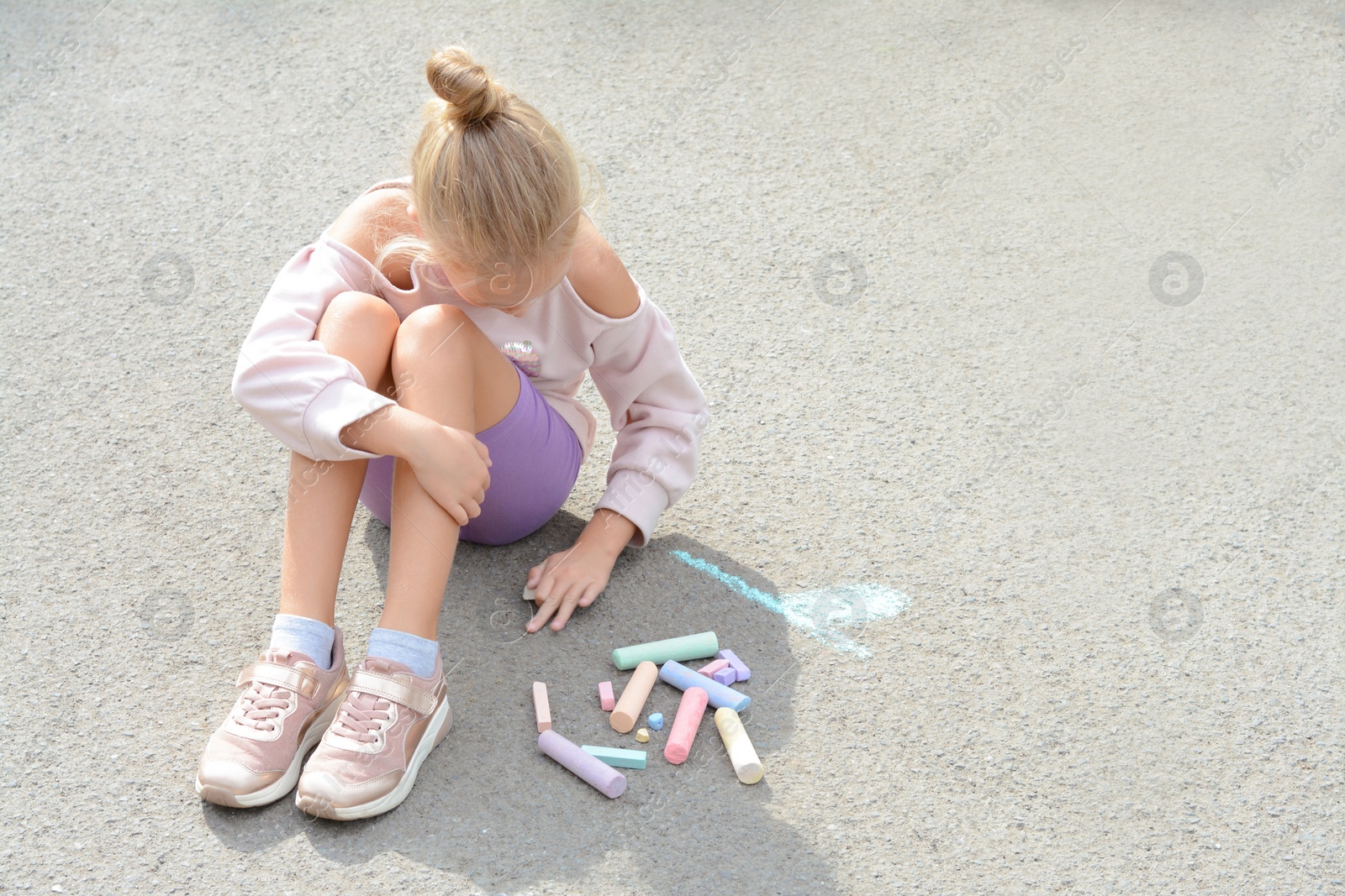 Photo of Little child drawing flower with chalk on asphalt, space for text