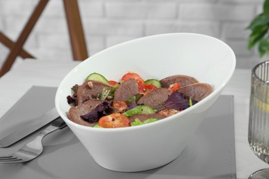 Photo of Delicious salad with beef tongue and vegetables served on table, closeup