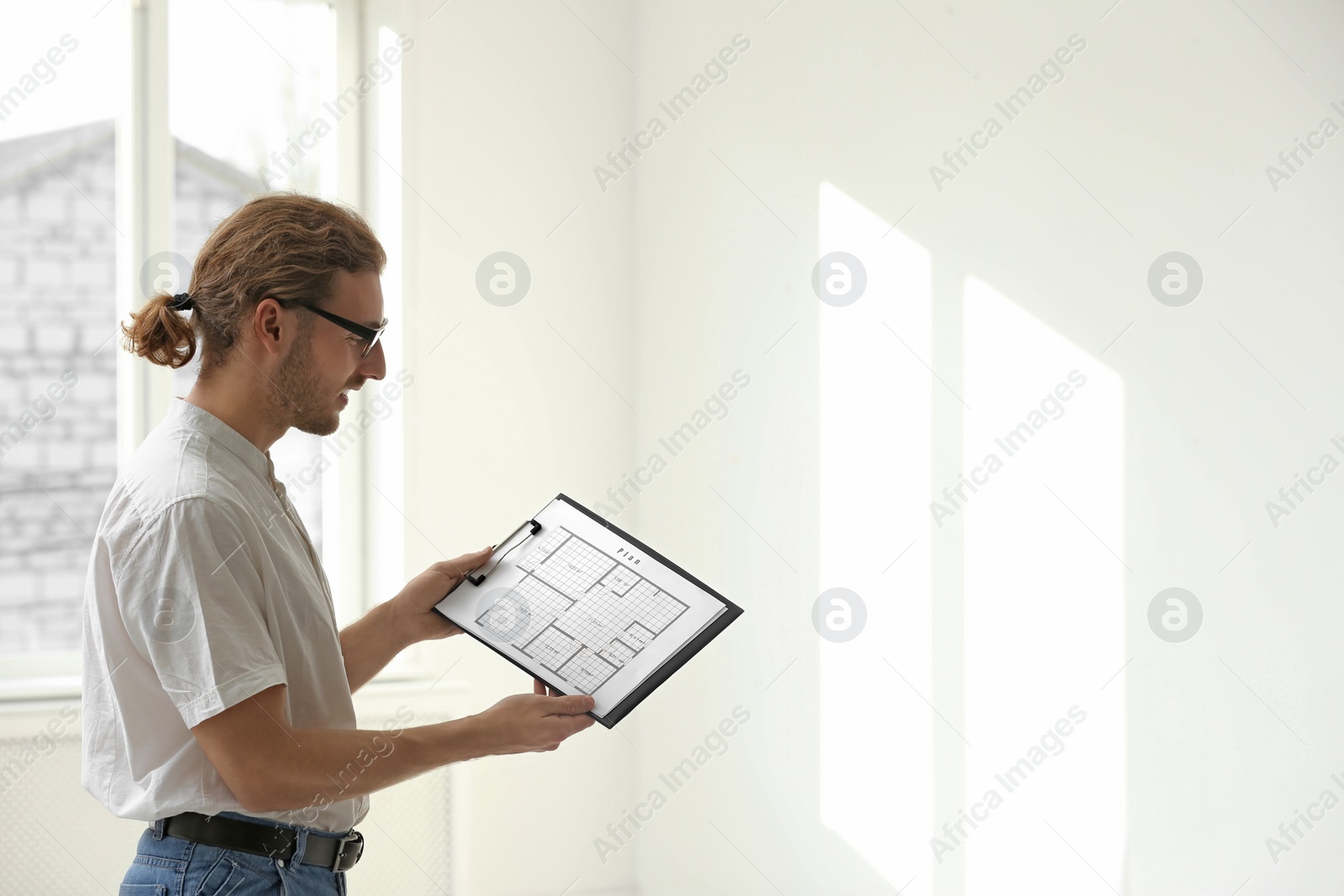 Photo of Professional interior designer with clipboard in empty apartment. Space for text