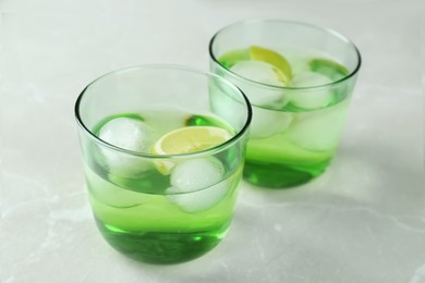 Photo of Delicious cocktails with lime and ice balls on grey table