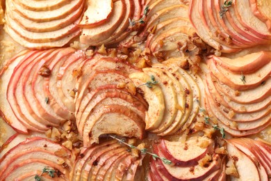 Photo of Freshly baked apple pie with nuts as background, top view