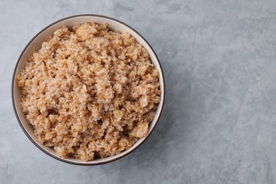 Tasty wheat porridge in bowl on grey table, top view. Space for text