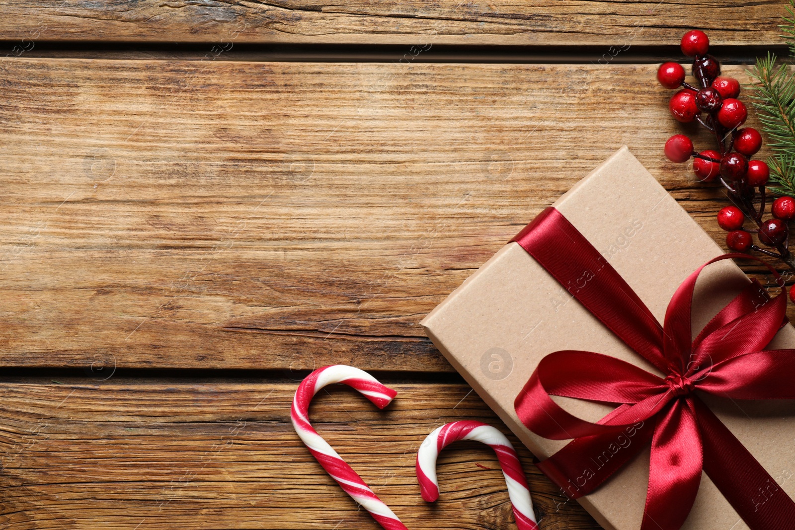 Photo of Gift box, candy canes and Christmas decor on wooden table, flat lay. Space for text