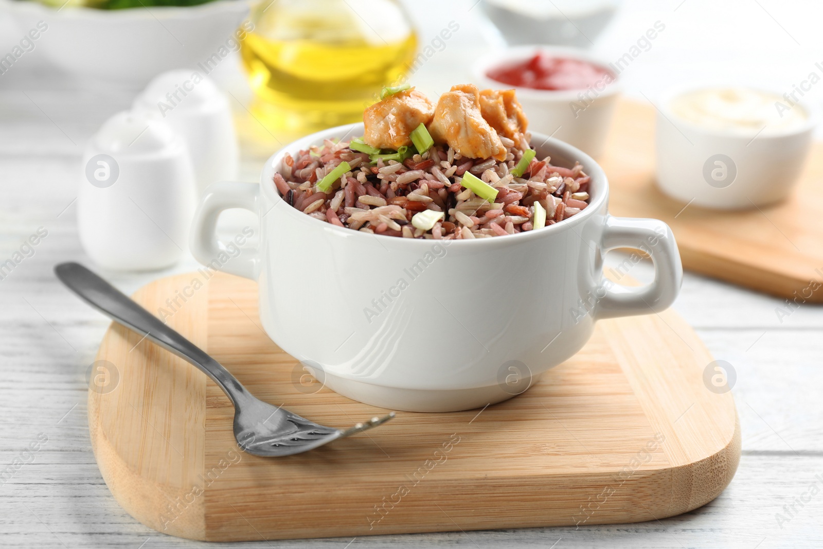 Photo of Delicious brown rice in bowl on white wooden table