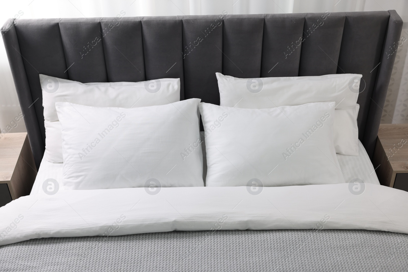 Photo of Soft white pillows and duvet on bed at home