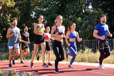 Photo of Group of people running at stadium on sunny day