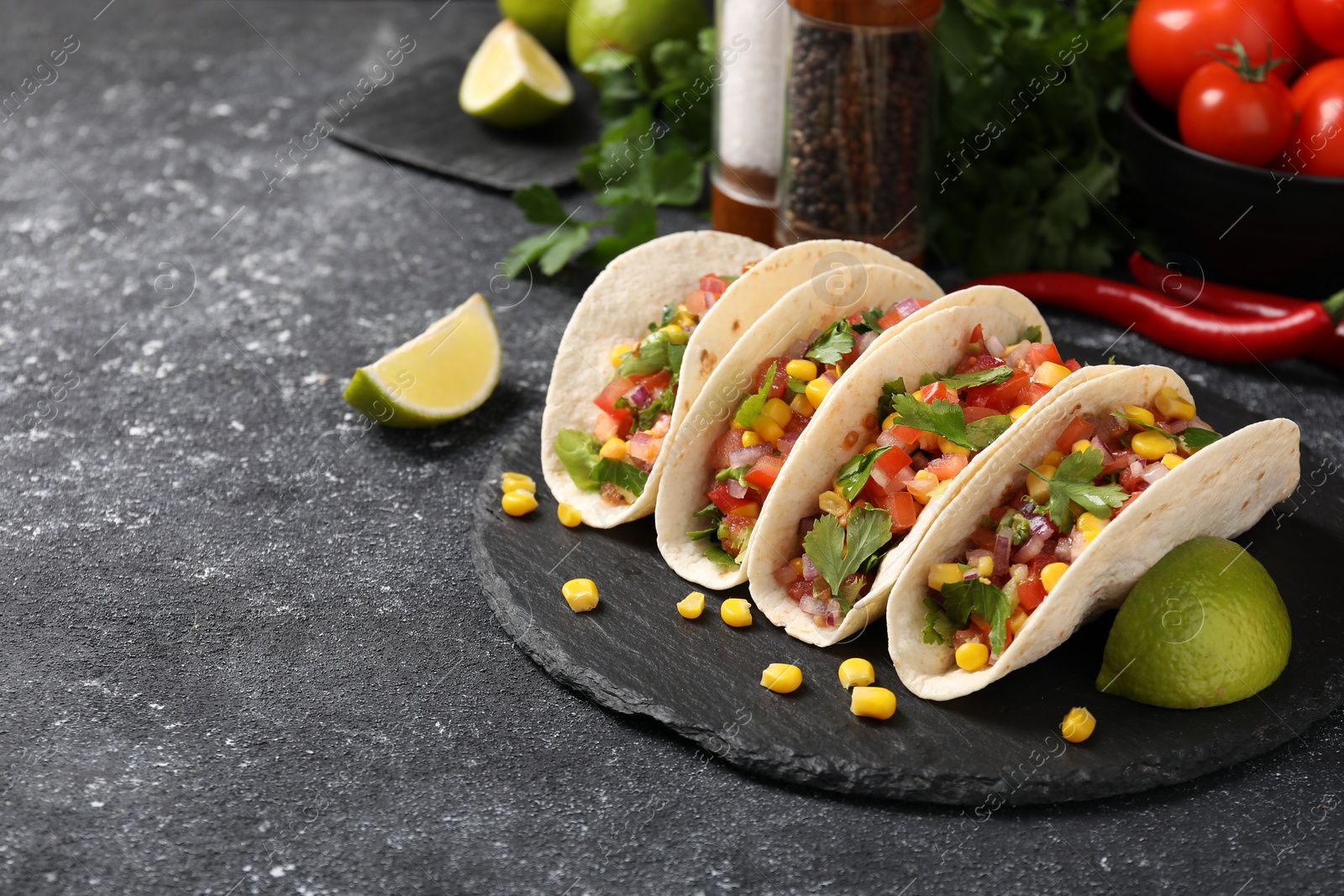 Photo of Tasty tacos with vegetables on black textured table, space for text