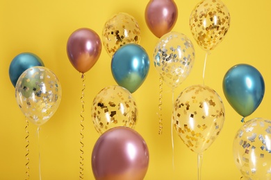 Bright balloons with ribbons on color background