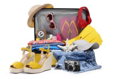 Photo of Open suitcase with clothes, beach accessories and shoes isolated on white. Summer vacation