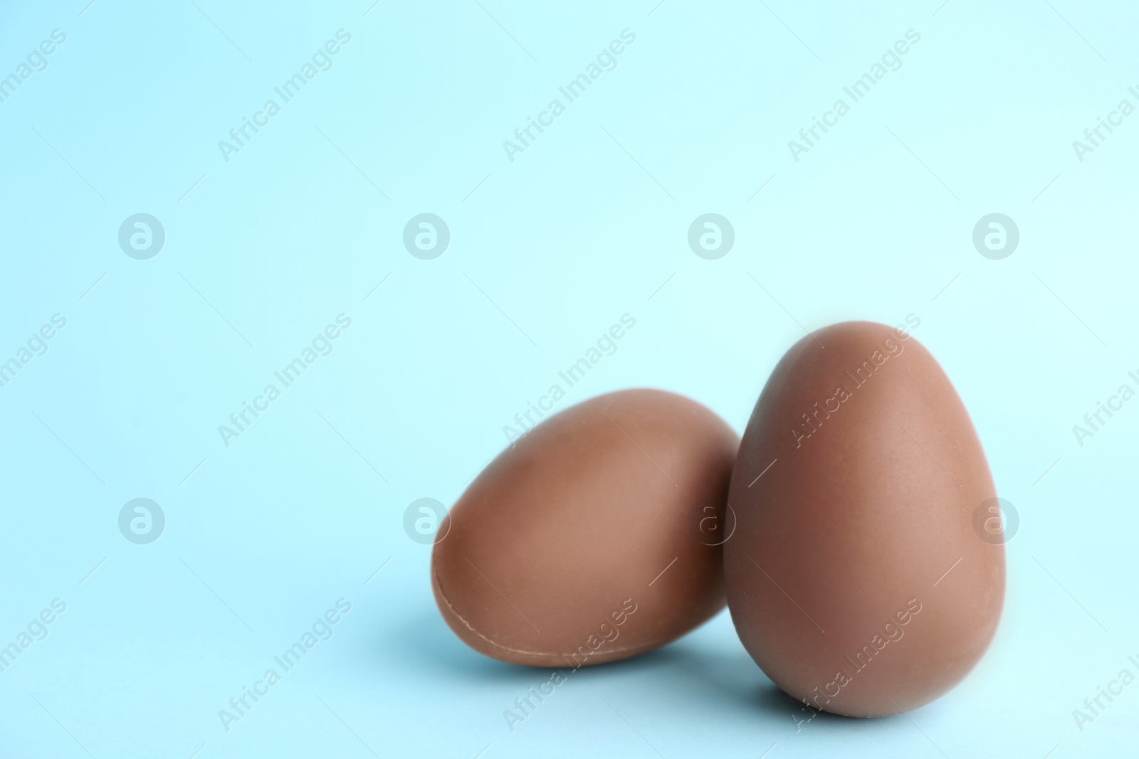 Photo of Sweet chocolate eggs on light blue background. Space for text