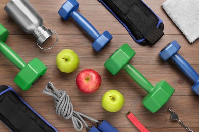 Flat lay composition with dumbbells on wooden table