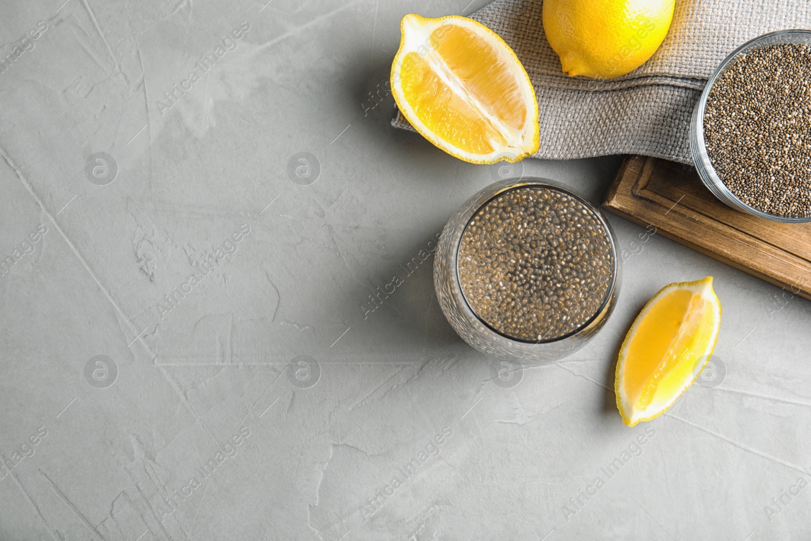 Photo of Flat lay composition with glass of water and chia seeds on grey background, space for text