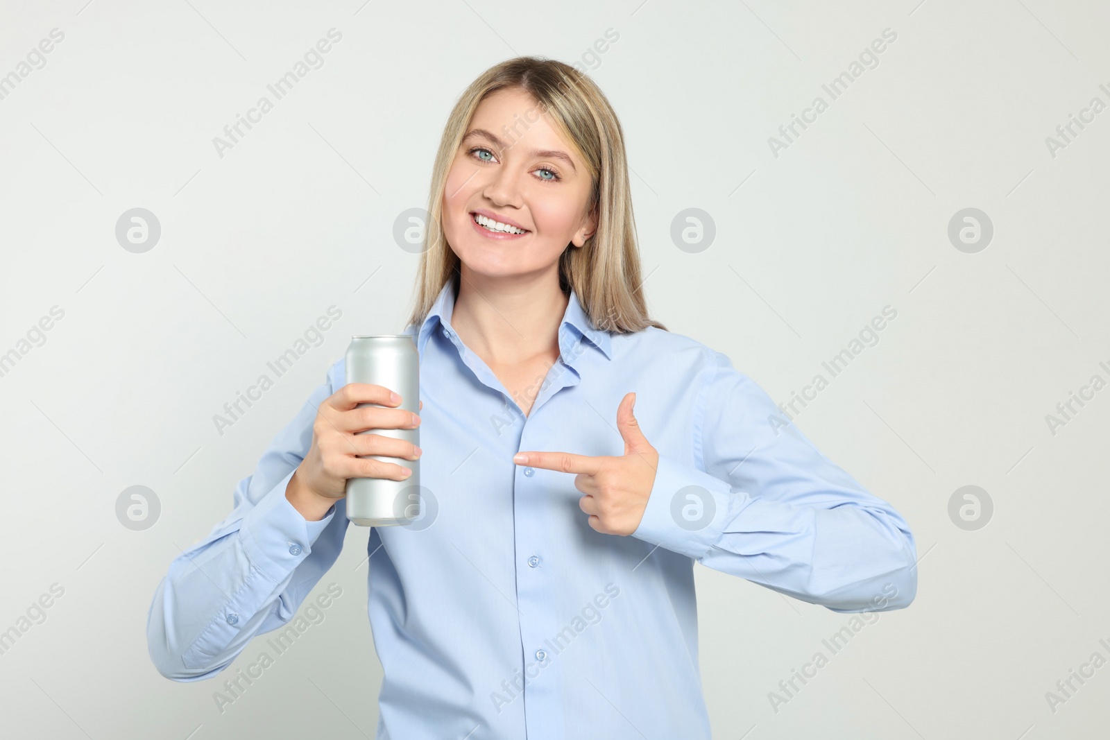 Photo of Beautiful happy woman holding beverage can on light background
