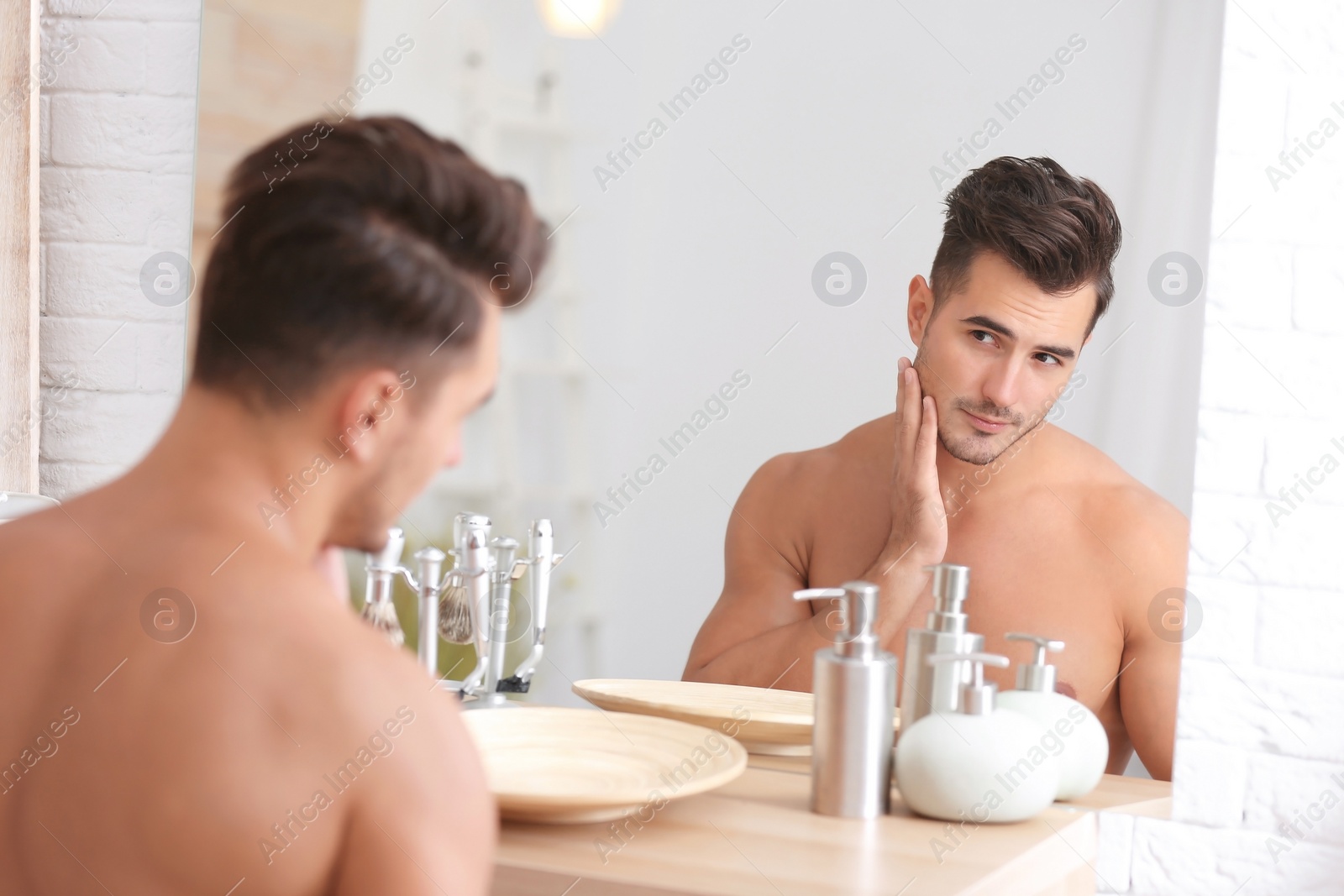 Photo of Young man with stubble ready for shaving near mirror in bathroom