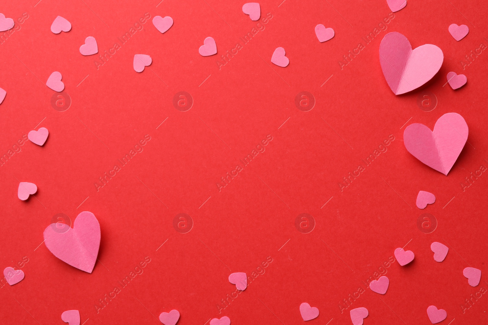 Photo of Framepink paper hearts on red background, flat lay. Space for text