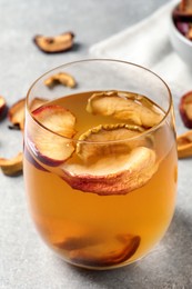 Delicious compote with dried apple slices in glass on grey table, closeup