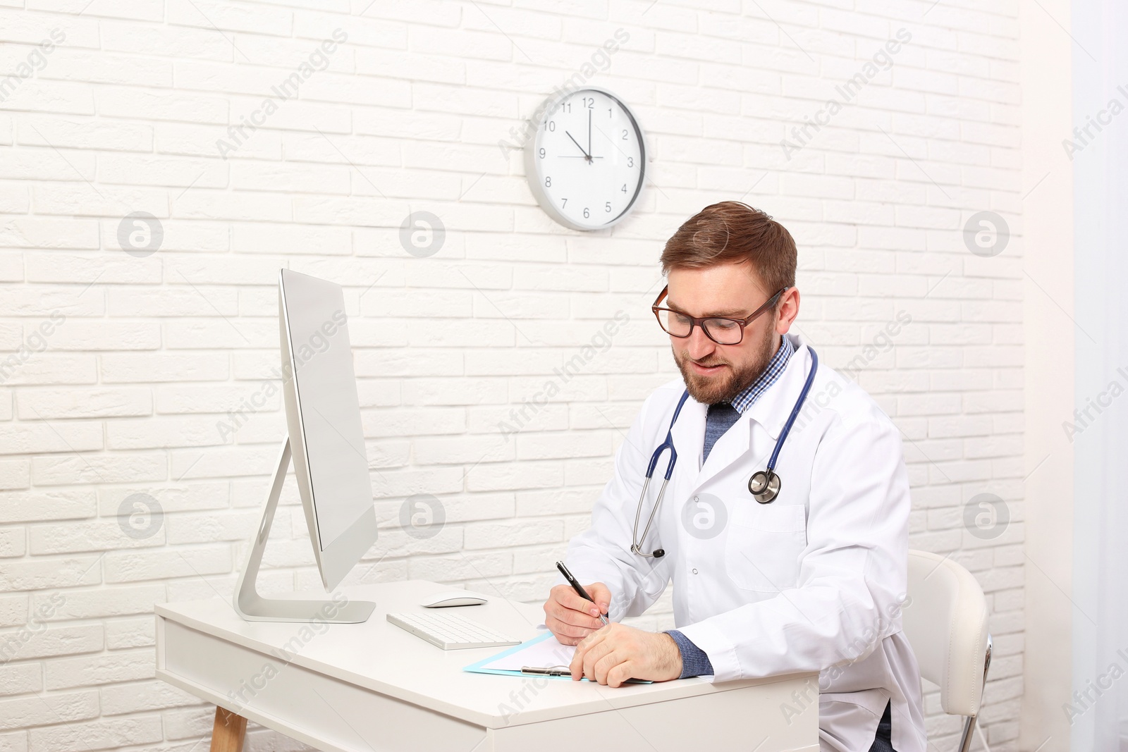 Photo of Pediatrician with clipboard working at table in clinic