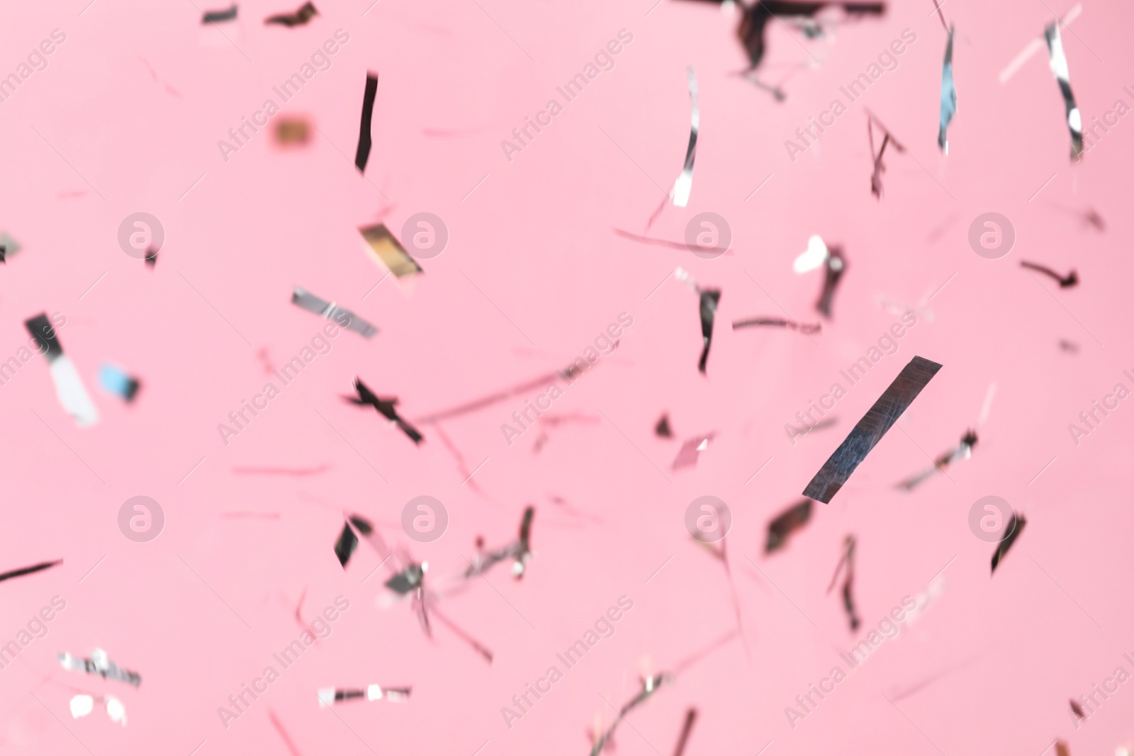 Photo of Shiny silver confetti falling down on pink background