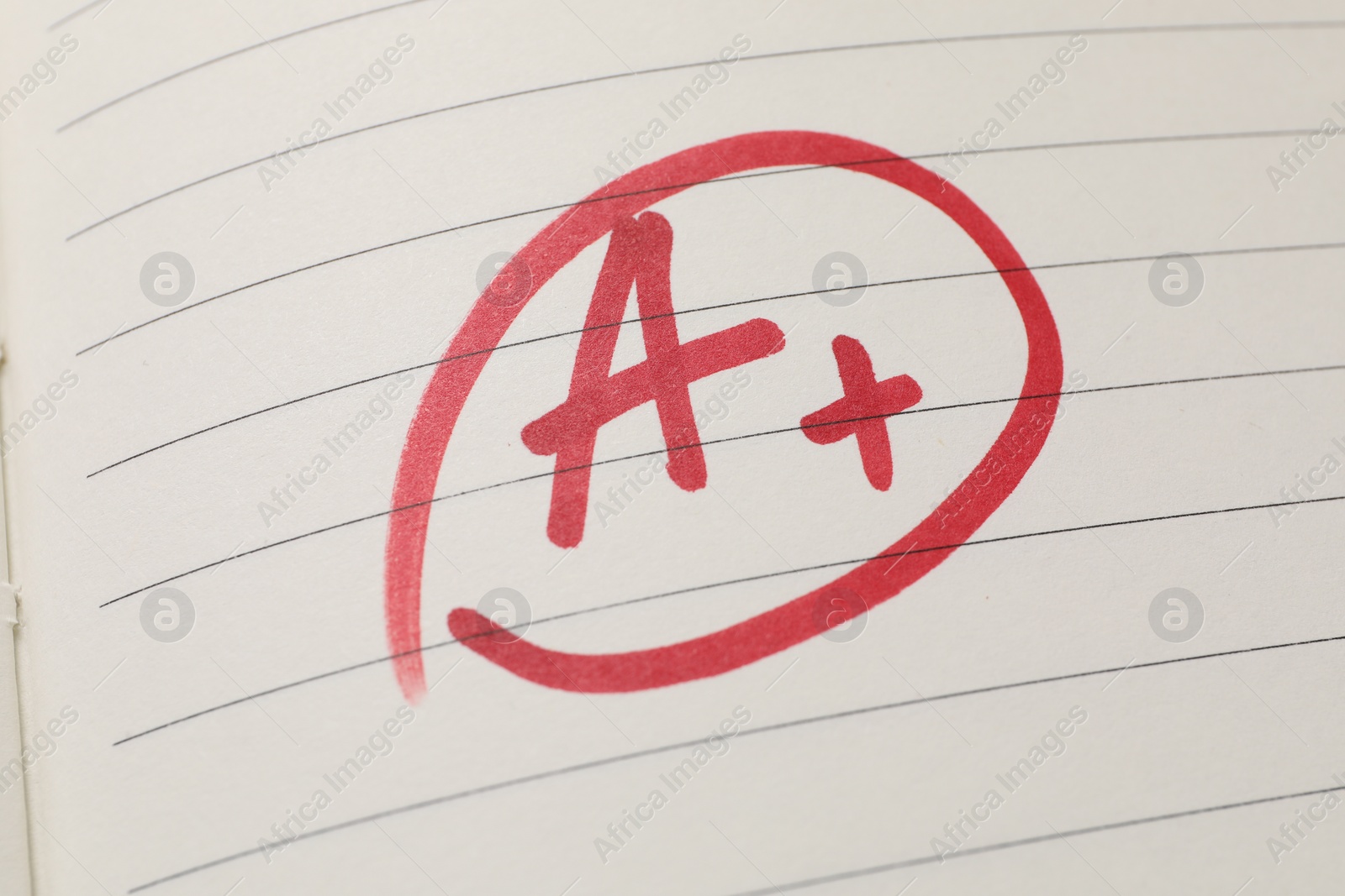 Photo of School grade. Red letter A with plus symbol on notebook paper, top view