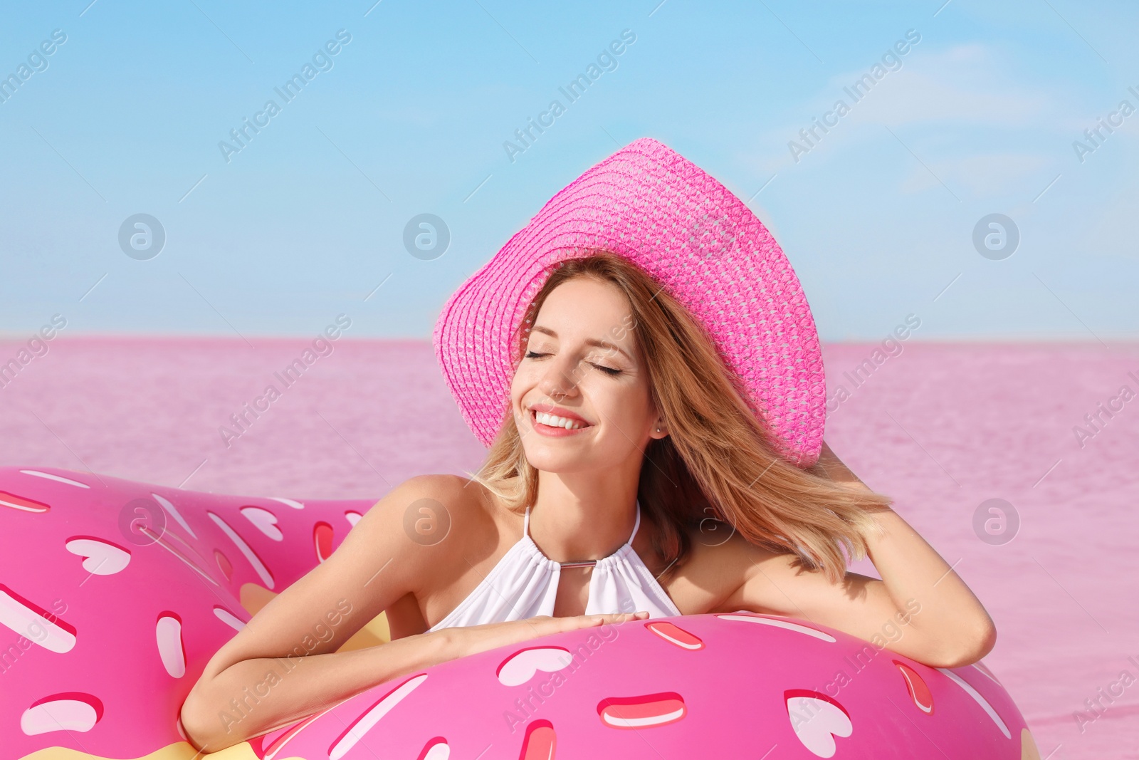 Photo of Beautiful woman with inflatable ring near pink lake