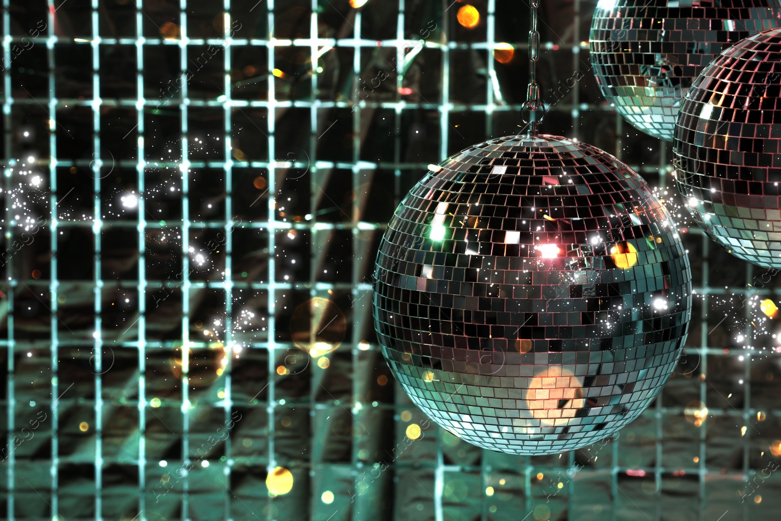 Image of Shiny disco balls against foil party curtain under color lights, space for text. Bokeh effect