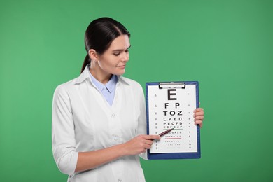 Photo of Ophthalmologist pointing at vision test chart on green background