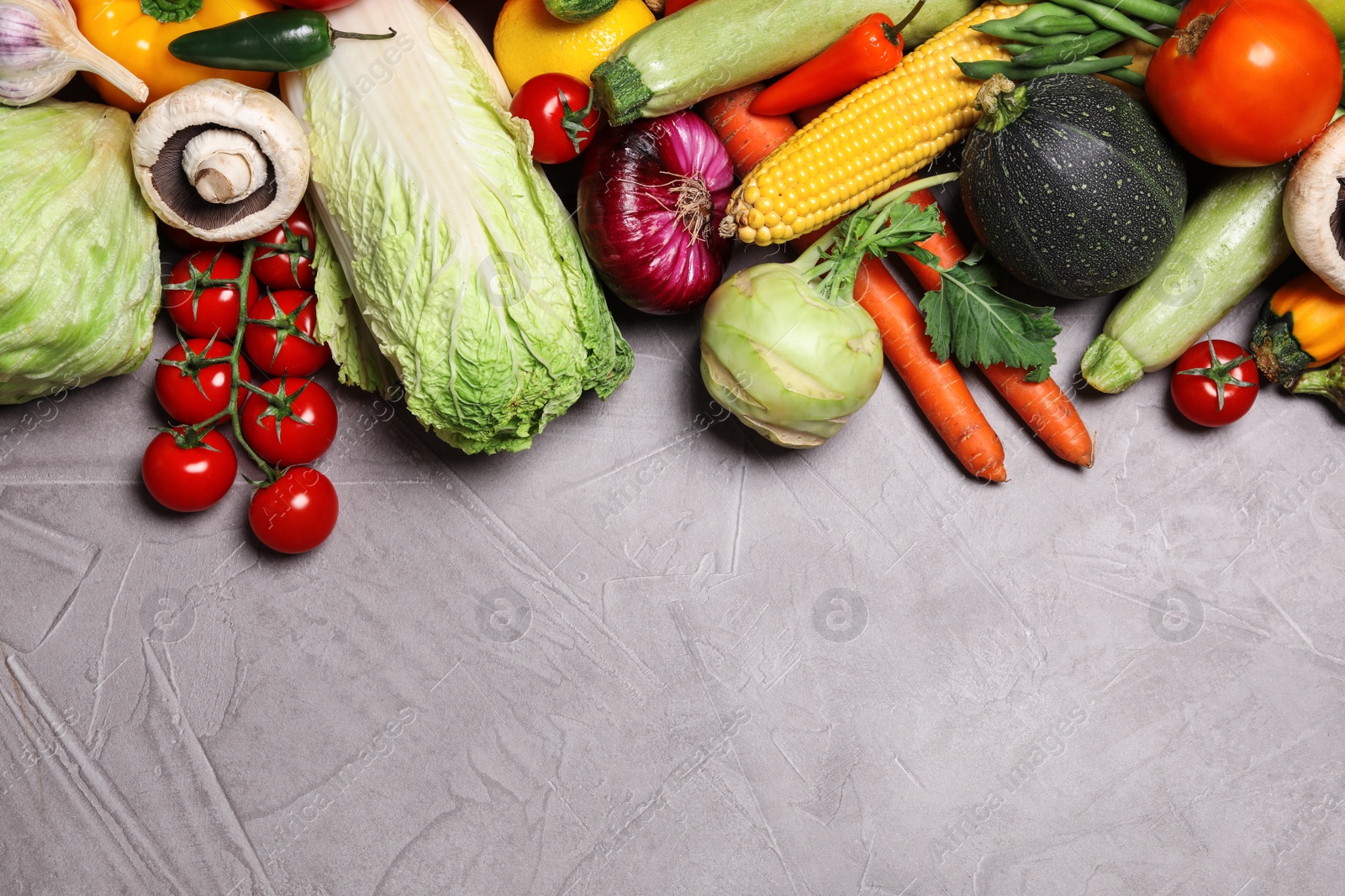 Photo of Different fresh vegetables on grey background, flat lay. Space for text