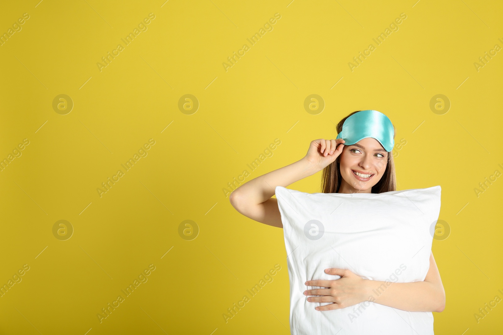 Photo of Young woman with pillow and sleep mask on yellow background. Space for text