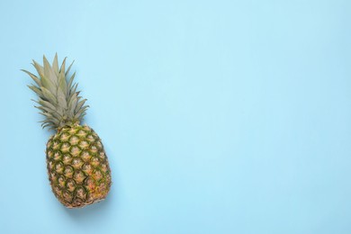 Whole ripe pineapple on light blue background, top view. Space for text