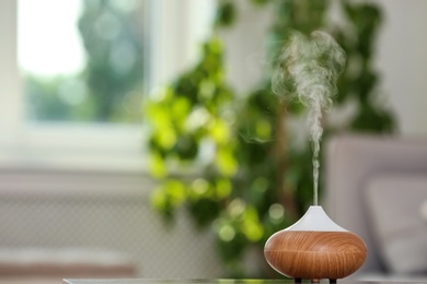 Aroma oil diffuser lamp on table against blurred background