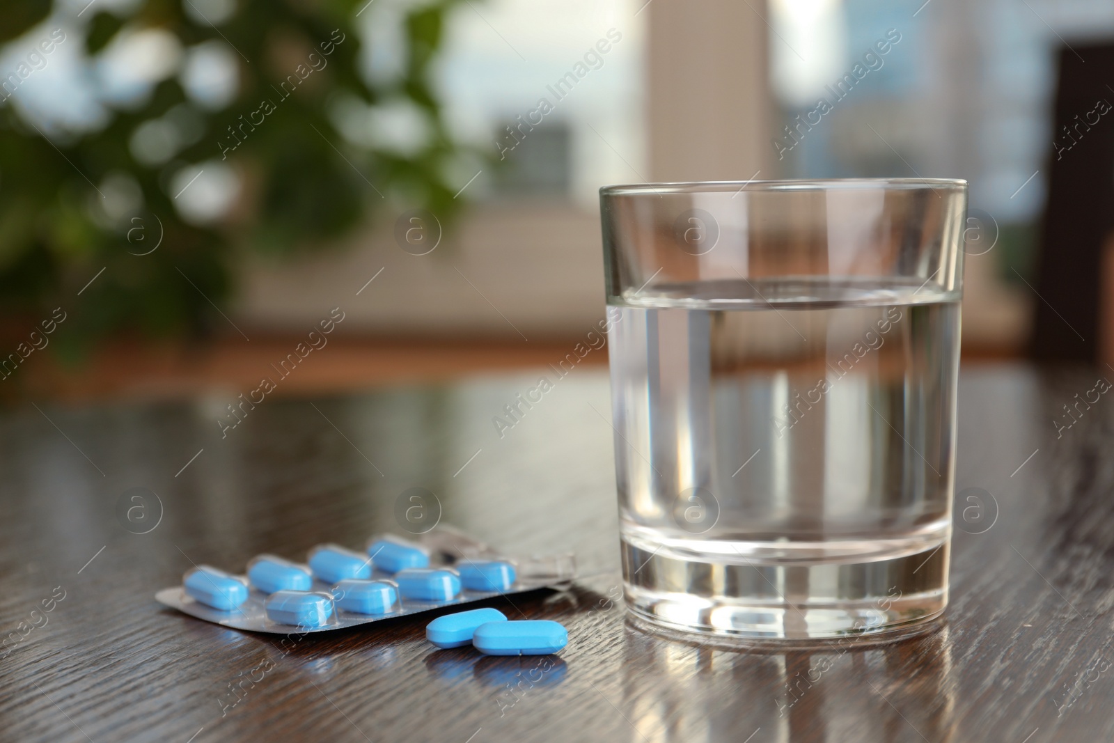 Photo of Glass of water and pills on wooden table indoors, space for text. Potency problem concept