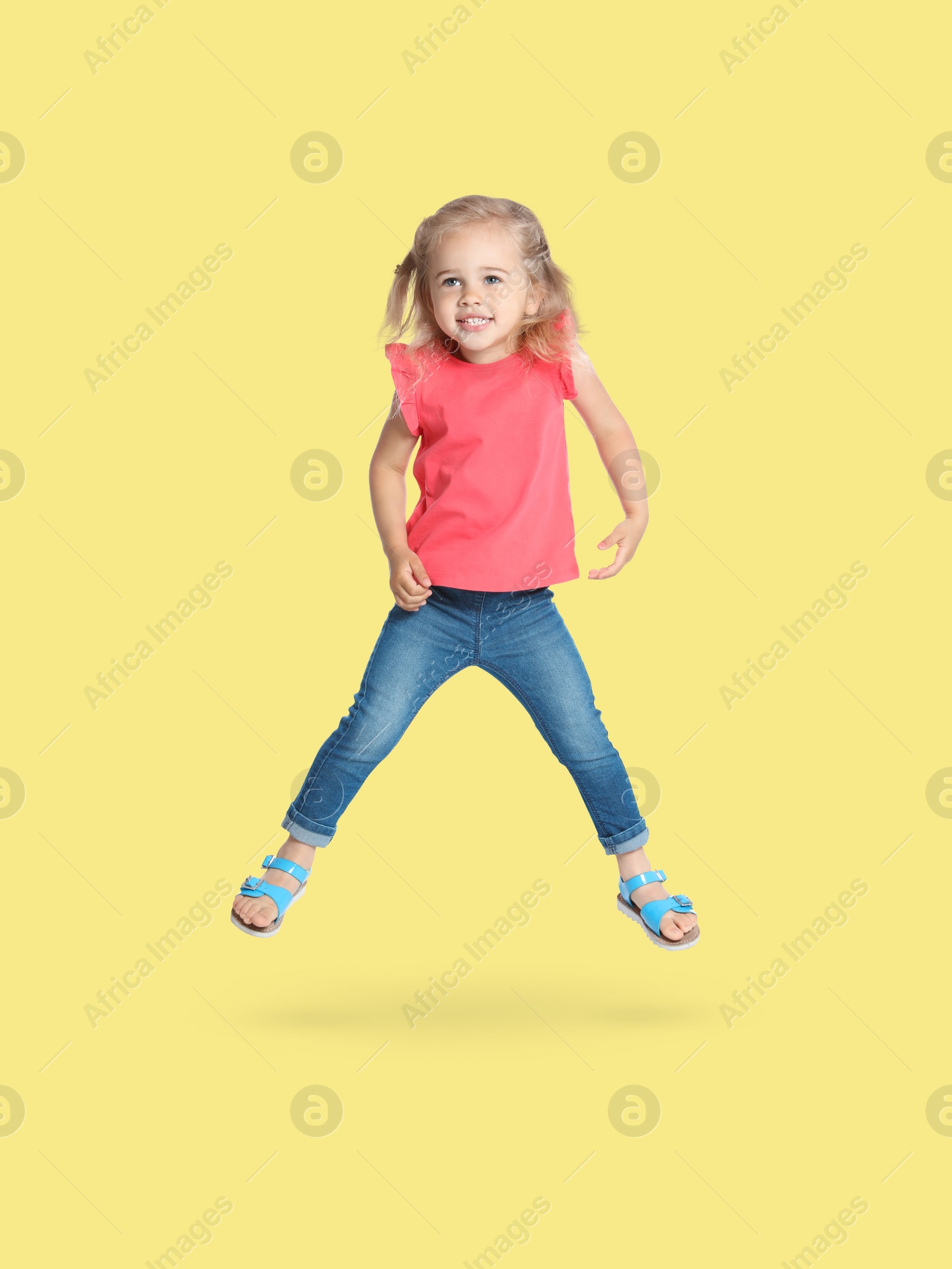 Image of Happy cute girl jumping on beige background