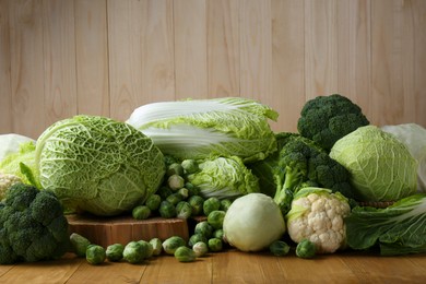 Photo of Many different types of fresh cabbage on wooden table